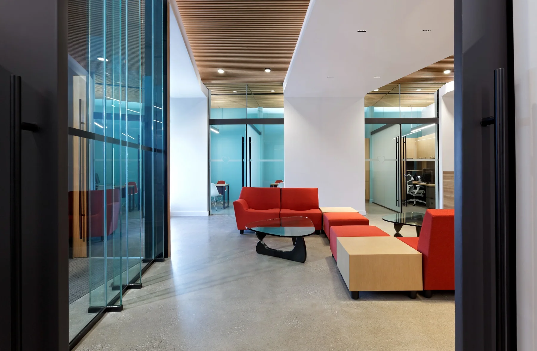Clinic waiting room with red sofas and wood-slat ceiling